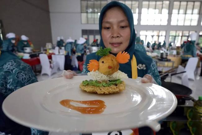 Seorang peserta memperlihatkan makanan berbahan baku ikan saat Lomba Cipta Menu Ikan di Kabupaten Kediri, Jawa Timur, Rabu (3/12/2025). Kegiatan yang diselenggarakan Pemkab Kediri tersebut sebagai upaya mendorong ibu rumah tangga menciptakan menu makanan sehat berbahan baku ikan dengan tampilan yang menarik agar anak gemar makan ikan guna mencegah stunting. (Antara Foto/Prasetia Fauzani)
