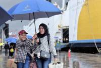 Seorang anak dan ibu menggunakan payung menuju terminal kedatangan di tengah cuaca hujan usai turun dari Kapal Motor (KM) Dharma Kartika II di Pelabuhan Trisakti, Banjarmasin, Kalimantan Selatan, Senin (30/3/2026). (Antara/Tumpal A Aritonang)