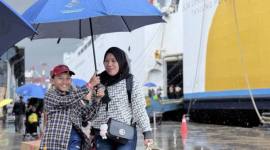 Seorang anak dan ibu menggunakan payung menuju terminal kedatangan di tengah cuaca hujan usai turun dari Kapal Motor (KM) Dharma Kartika II di Pelabuhan Trisakti, Banjarmasin, Kalimantan Selatan, Senin (30/3/2026). (Antara/Tumpal A Aritonang)
