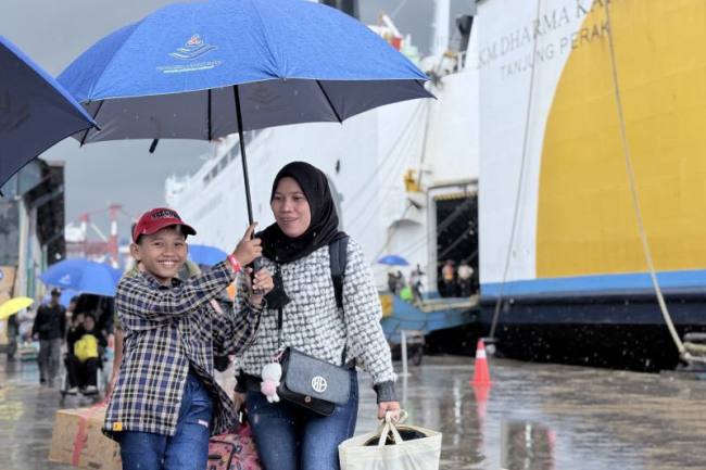 Seorang anak dan ibu menggunakan payung menuju terminal kedatangan di tengah cuaca hujan usai turun dari Kapal Motor (KM) Dharma Kartika II di Pelabuhan Trisakti, Banjarmasin, Kalimantan Selatan, Senin (30/3/2026). (Antara/Tumpal A Aritonang)
