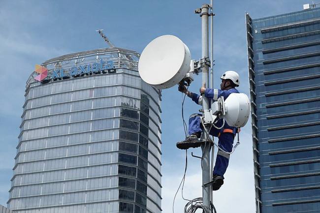Foto Ilustrasi - Seorang teknisi sedang memasang BTS di menara. (XL Axiata)