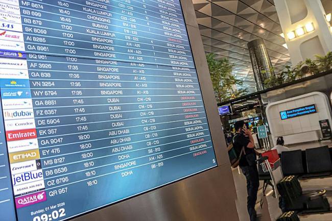 Calon penumpang berada di samping layar monitor pengumuman jadwal penerbangan pesawat di Terminal 3 Bandara Soekarno Hatta, Tangerang, Banten, Minggu (1/3/2026). Akibat terjadinya perang antara Iran, Israel dan Amerika sejumlah maskapai yang melayani penerbangan ke Timur Tengah membatalkan sejumlah penerbangannya. (Antara Foto/M Iqbal)