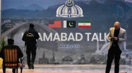 Petugas keamanan berada di dekat baliho perundingan AS-Iran di luar pusat media di Islamabad, Pakistan, Minggu (12/4/2026). (AP/ANJUM NAVEED)