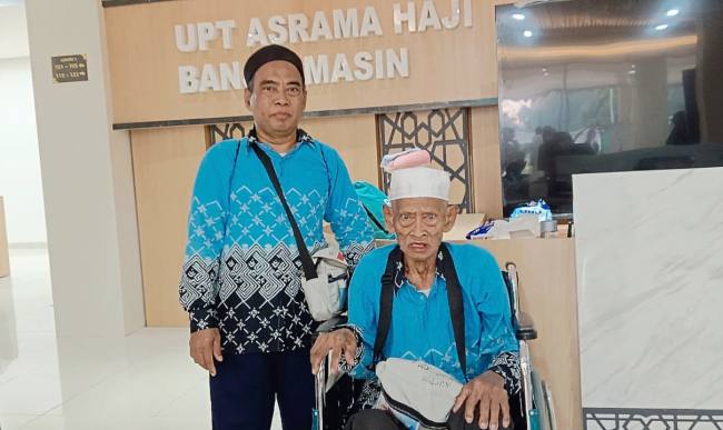 H Kasrun Sahidin Abdullah yang merupakan haji tertua Debarkasi Banjarmasin tahun 1447 H / 2026 M, yakni berusia 101 tahun dan sang anak saat tiba di tanah air pada Kloter 17 di asrama haji di Kota Banjarbaru, Minggu (28/6/2026). (Foto: PPIH Debarkasi Banjarmasin)