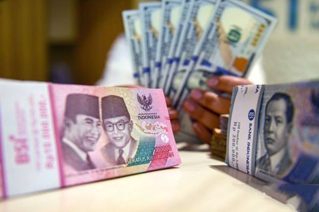 Petugas menunjukan uang pecahan dolar AS dan rupiah di Bank BSI, Jakarta, Selasa (3/9/2024). (Foto: Dok Antara)