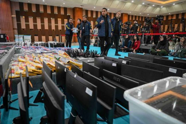 Petugas kepolisian mengecek barang bukti yang ditampilkan saat konferensi pers kasus judi online jaringan internasional, di Bareskrim Mabes Polri, Jakarta, Jumat (26/6/2026). (Foto: Antara/Fauzan/kye)