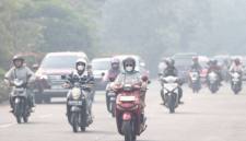 Beberapa pengendara motor mengenakan masker ketika melintasi jalan yang diliputi asap akibat kebakaran hutan dan lahan di Pontianak, Kalimantan Barat, Kamis (5/3/2026). (Foto: Dok Antara/Jessica Wuysang)