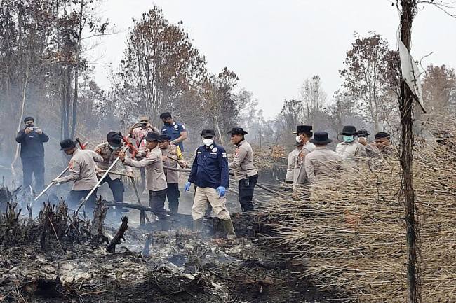Personel Polda Kalteng menyuntikkan cairan pemadam api surfaktan ke dalam lahan gambut yang terbakar di Petuk Katimpun, Kota Palangka Raya, Selasa (8/9/2026). (Foto: Antara/Rajib Rizali)
