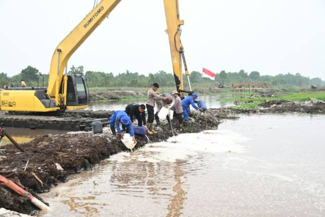 penanganan kebakaran hutan dan lahan (karhutla) menggunakan campuran cairan surfaktan dan helikopter water bombing di embung buatan Jalan Gubernur Syarkawi, Kabupaten Banjar, Selasa (27/10/2026) sore. (SuarIndonesia/Polda Klasel)